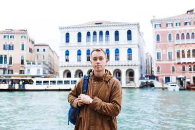 Young blond guy in a brown jacket in middle of streets of venice