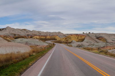 Empty road along landscape against sky