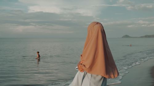 Woman standing on beach against sky