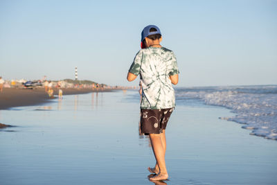 Full length of man standing at beach against clear sky