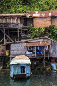 Houses by river against buildings