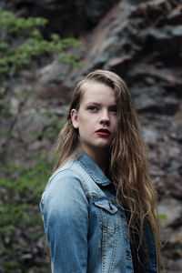 Side view of thoughtful woman looking away while standing against rock formations