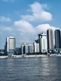 Sea by buildings against sky in city