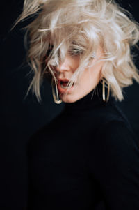 Portrait of woman smoking over black background
