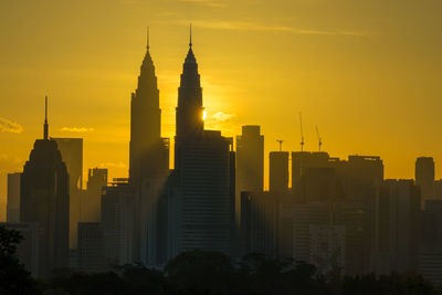 Silhouette of buildings in city during sunrise