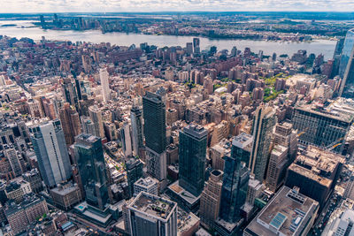 Aerial view of illuminated skyscraper buildings in city at day at high angle