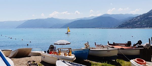 Boats moored in sea against mountains