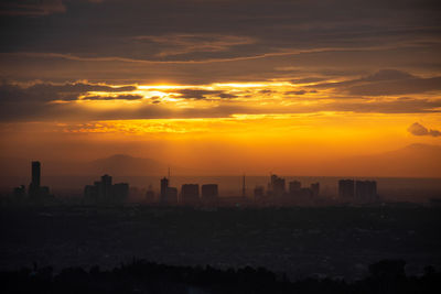 Silhouette buildings against sky during sunset