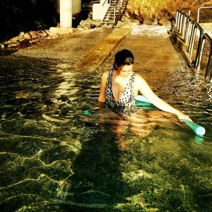 Rear view of woman sitting in water