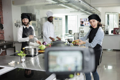 Food vlogger recording while preparing food at restaurant kitchen
