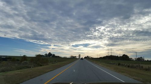 Country road against cloudy sky