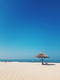 Lifeguard hut on beach against clear blue sky