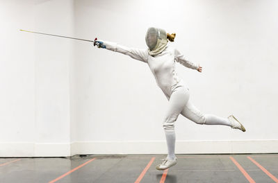 Woman in fencing outfit practicing at gym