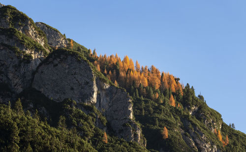 Low angle view of rocks against clear blue sky at lago di braies in dolomites mountains 