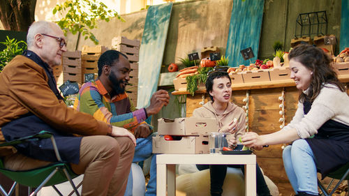 Portrait of smiling friends using mobile phone while sitting at restaurant