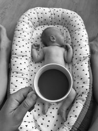 High angle view of hand holding coffee cup over baby