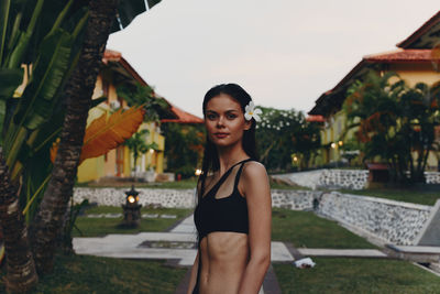 Portrait of young woman standing against built structures