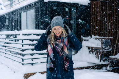 Happy laughing woman stands under snowfall.