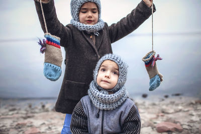 Cute cheerful sibling sitting by lake during winter