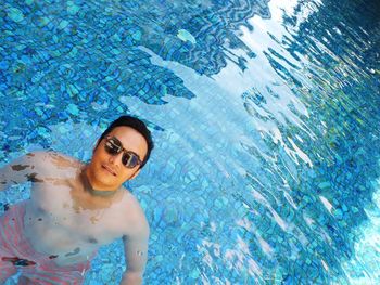 High angle portrait of shirtless man swimming in pool