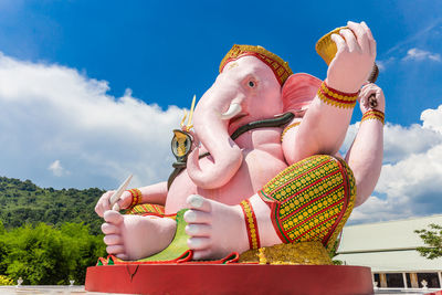 Low angle view of woman holding toy sculpture against sky