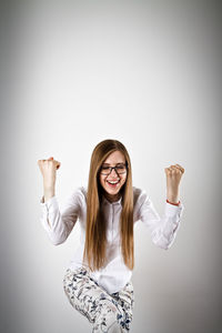 Portrait of smiling young woman standing against white background