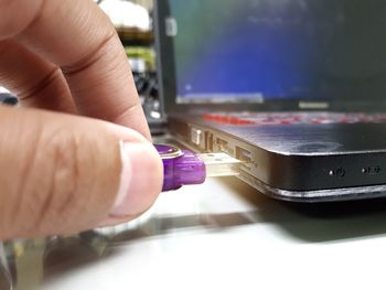 Close-up of person inserting usb stick in laptop