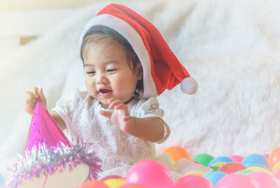 Cute baby girl wearing santa hat on bed at home