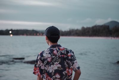 Rear view of man standing by sea against sky