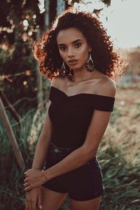 Portrait of beautiful young woman standing by tree