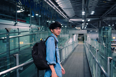 Young woman looking away while standing on illuminated railing