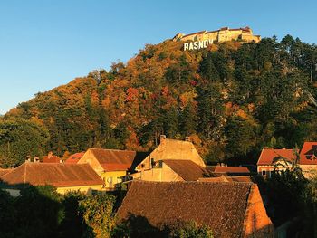 Trees and buildings against sky during autumn