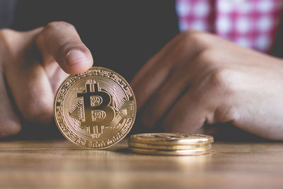 Cropped hands of business person holding bitcoin over wooden table