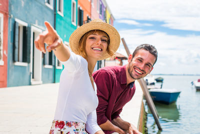 Portrait of happy friends standing against water