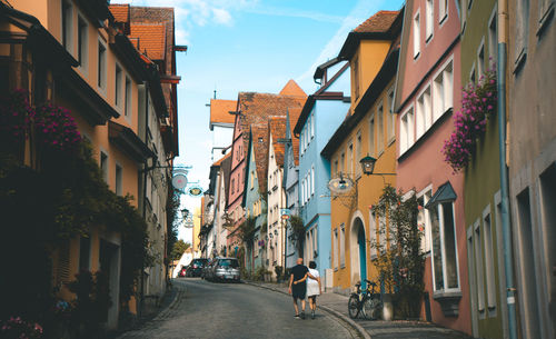 People walking on footpath amidst buildings in city