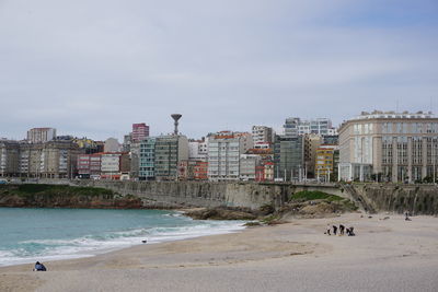 View of beach by buildings in city against sky