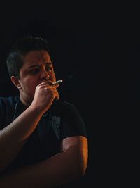 Young man holding cigarette in the dark