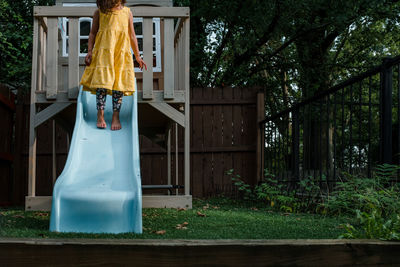 Little girl in yellow dress standing on blue slide