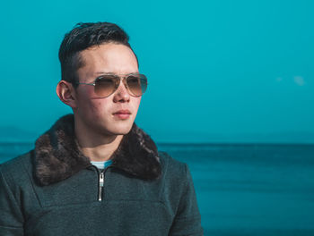 Close-up of man wearing sunglasses standing against sea