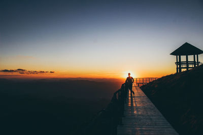 Silhouette man standing on observation point against sky during sunset