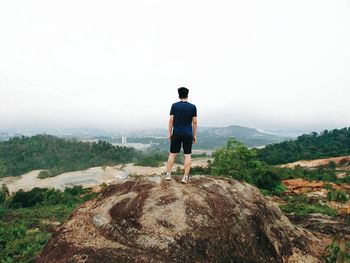 Rear view of man looking at mountain against sky