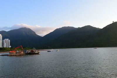 Scenic view of sea by mountains against sky