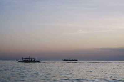 Boat sailing in sea against sky during sunset