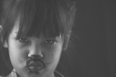 Close-up portrait of girl with face paint puckering lips against wall