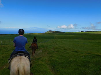 Rear view of man standing on field against sky