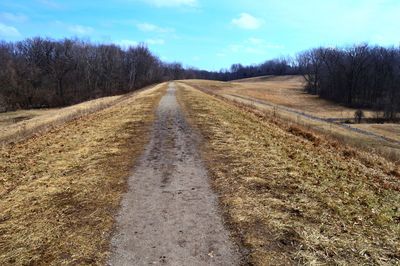 Road amidst field against sky