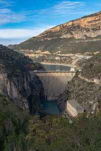 Water dam with hydroelectric installations between mountains in autumn