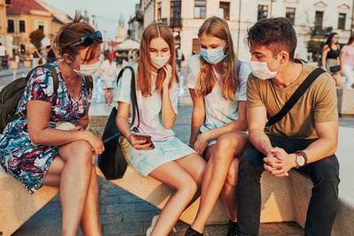 Family spending time together sitting in the city center. girls wearing the face masks