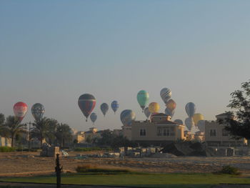 Hot air balloons on field against clear sky