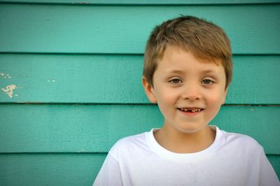 Portrait of smiling boy against green wall